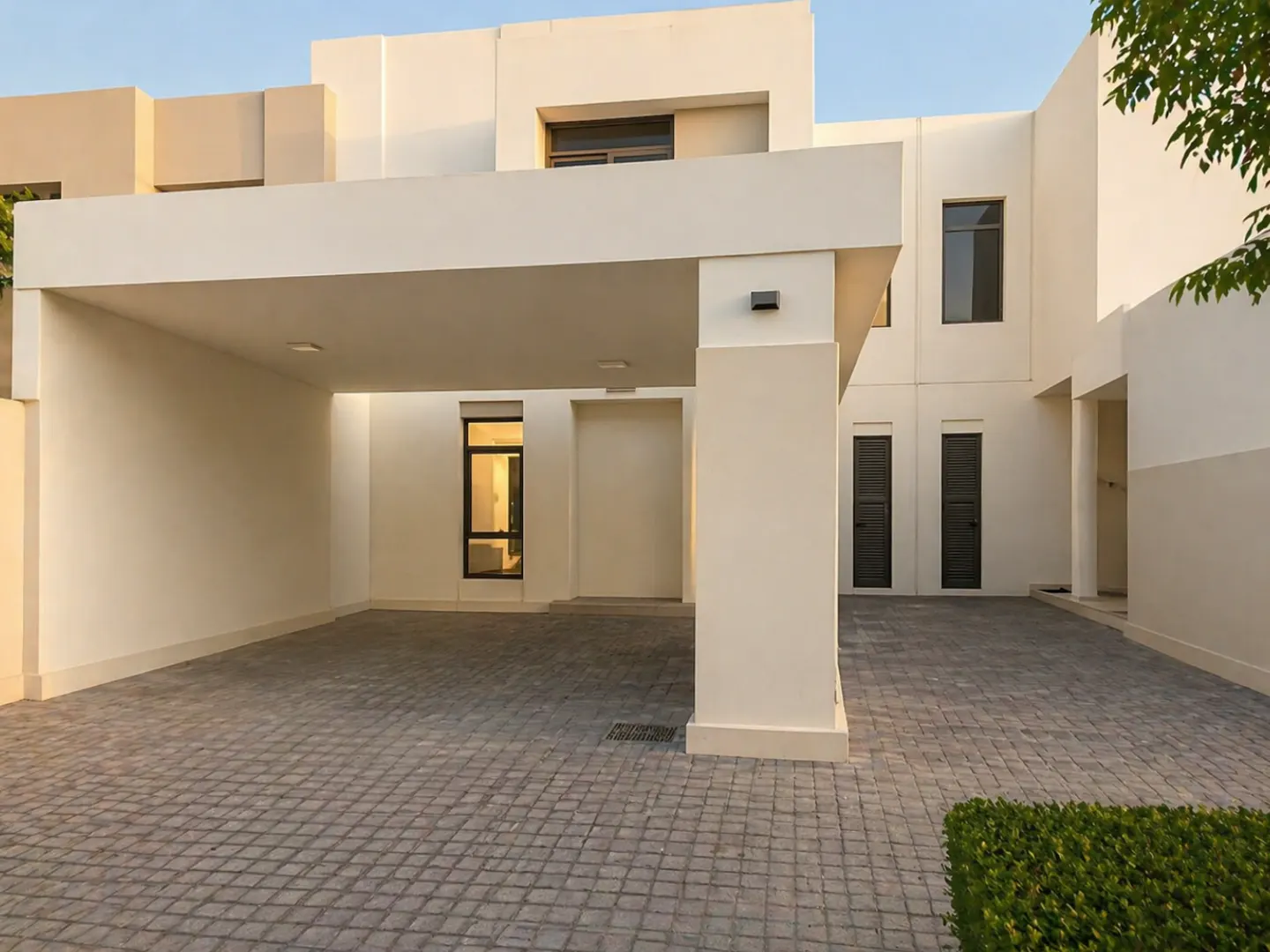 Exterior of a modern, two-story white house with a covered carport and a gray cobblestone driveway.