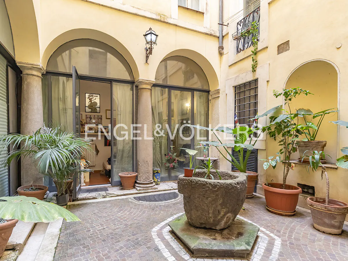 Courtyard view with stone planters, arched doorways, and brick-patterned floor. Engel & Völkers logo is visible.