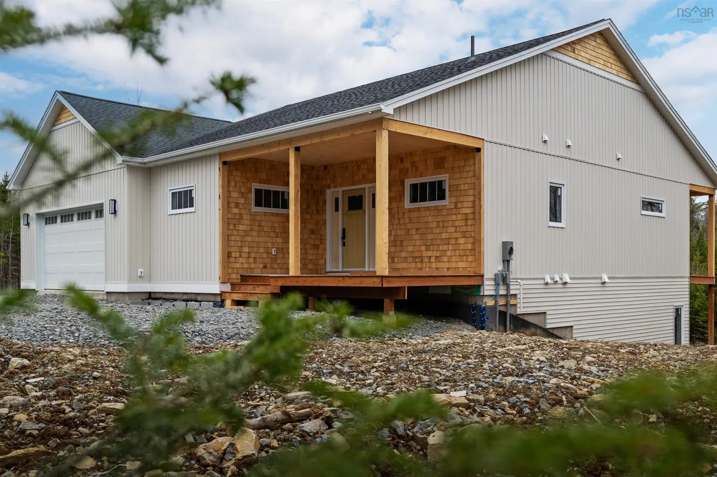 Exterior view of a one-story house with a garage, a wooden porch, and light-beige siding.