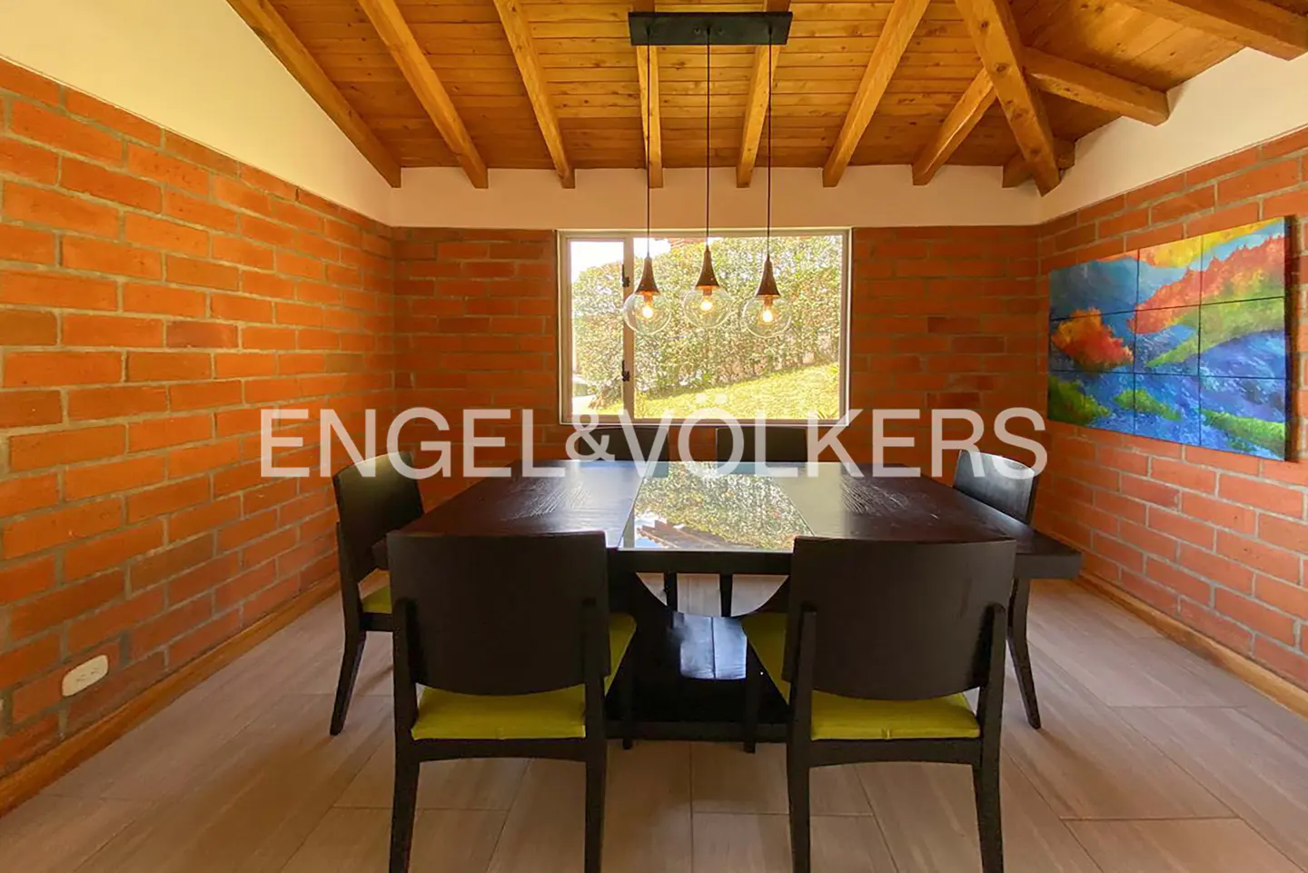 Dining room with brick walls, wood ceiling, and a dark wood table with six chairs. A window looks out onto a green lawn.