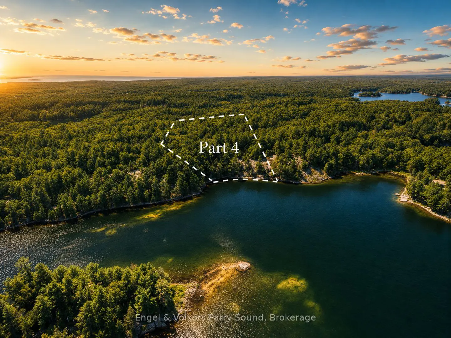 Aerial view of wooded land, "Part 4" outlined in white, bordering a lake at sunset.