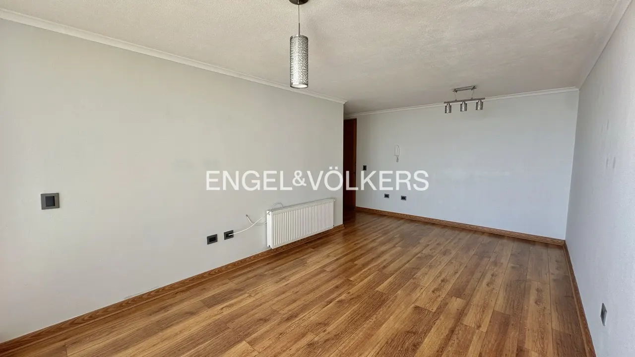 Empty room with wood floors, light gray walls, white trim, and two light fixtures. Engel & Völkers logo is superimposed.