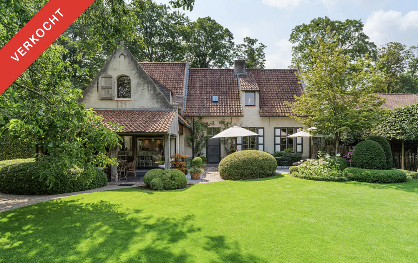 Sold! Exterior view of a two-story house with a red tile roof, green lawn, and manicured bushes. "Verkocht" banner in the upper left corner.