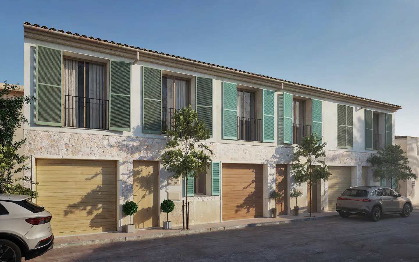 A two-story townhouse with stone facade, wooden garage doors, and green shutters, with cars parked on the street in front.
