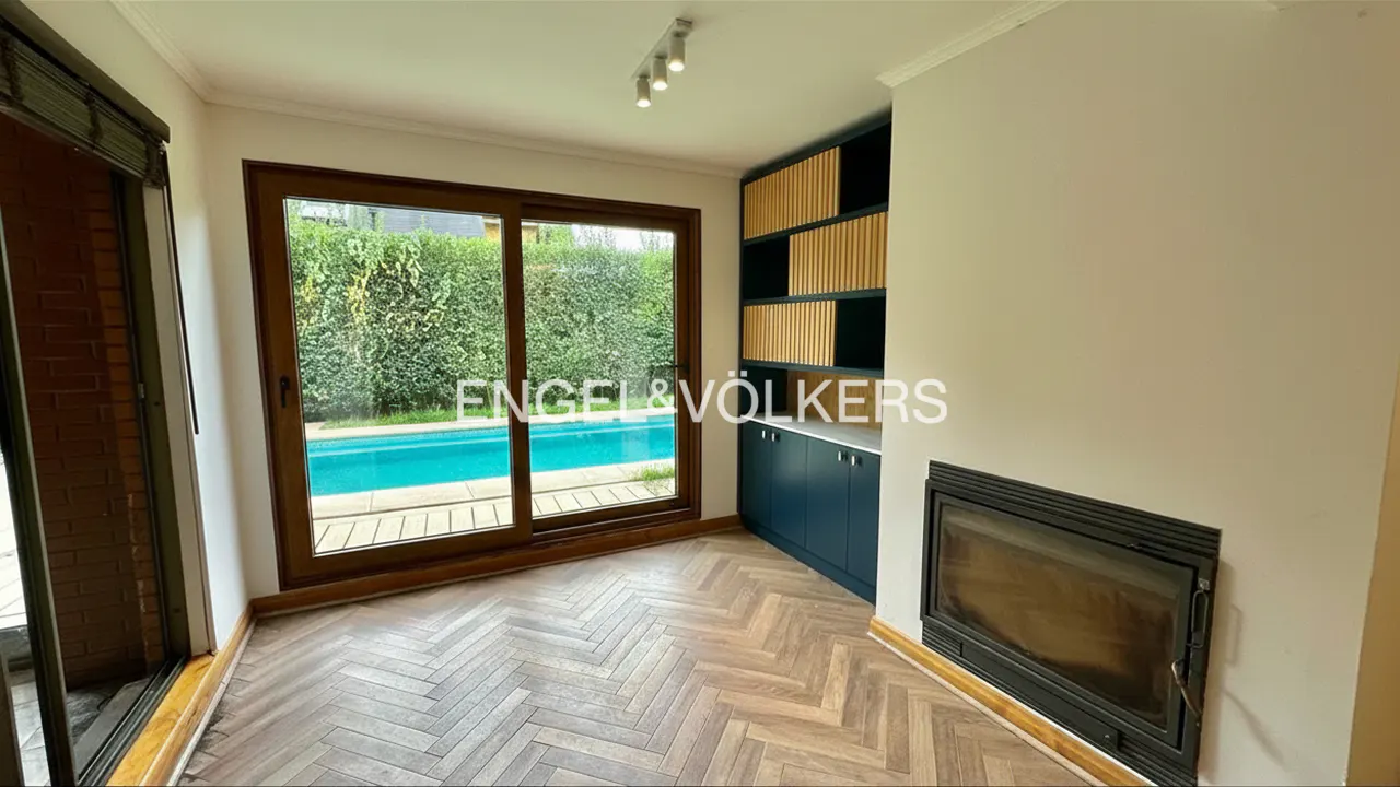 Living room with herringbone wood floors, a fireplace, and a built-in blue cabinet. Sliding glass doors lead to a pool.