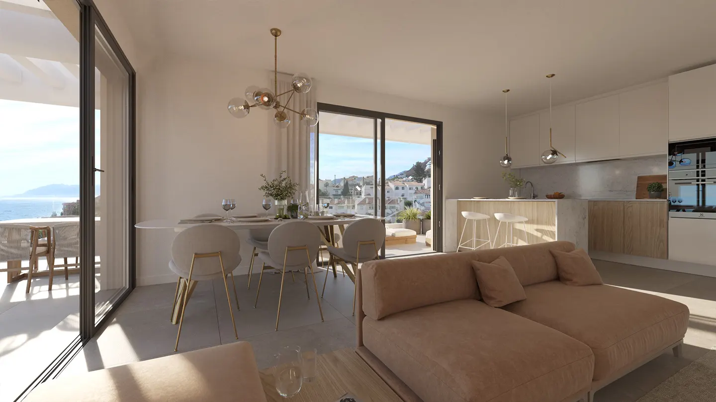 Bright, modern living space with a dining table, sofa, and kitchen. Large windows offer a view of the sea and a coastal town.
