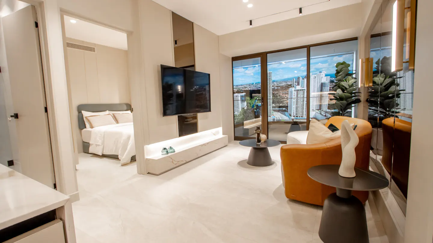 A modern apartment interior with a bedroom view, a TV, and a city view from the window.