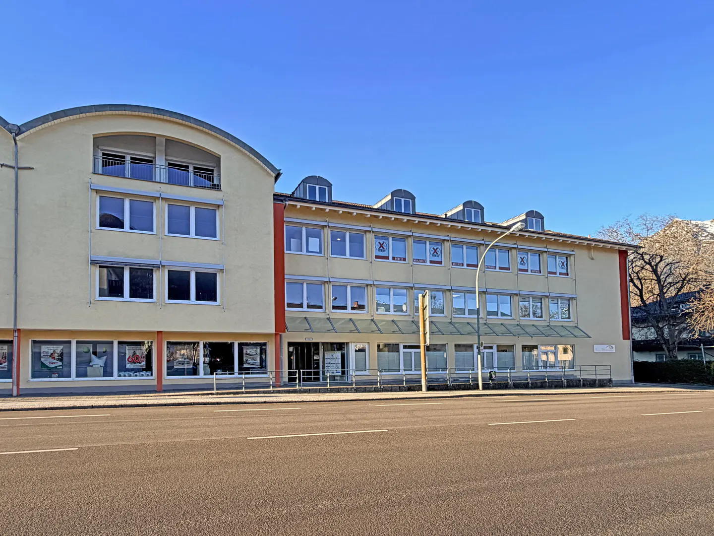 A three-story yellow building with many windows and a blue sky above.