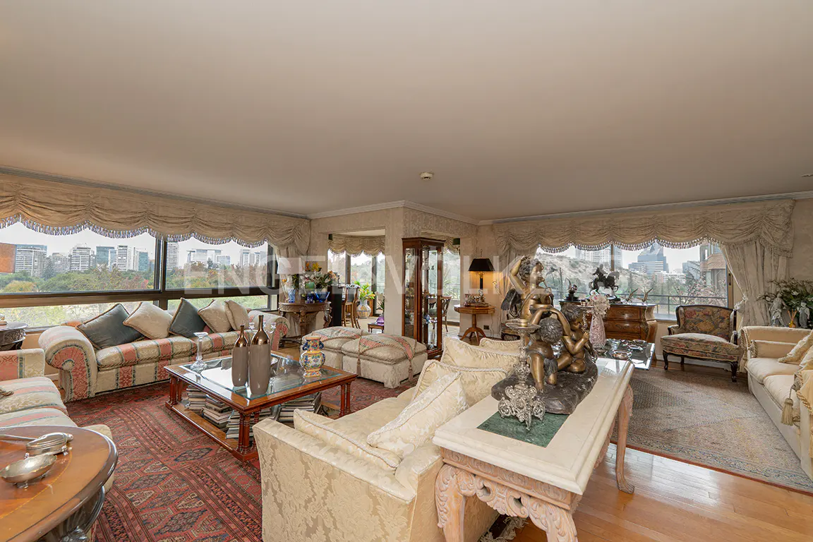 Wide shot of a luxurious living room with sofas, tables, and a city view through large windows.