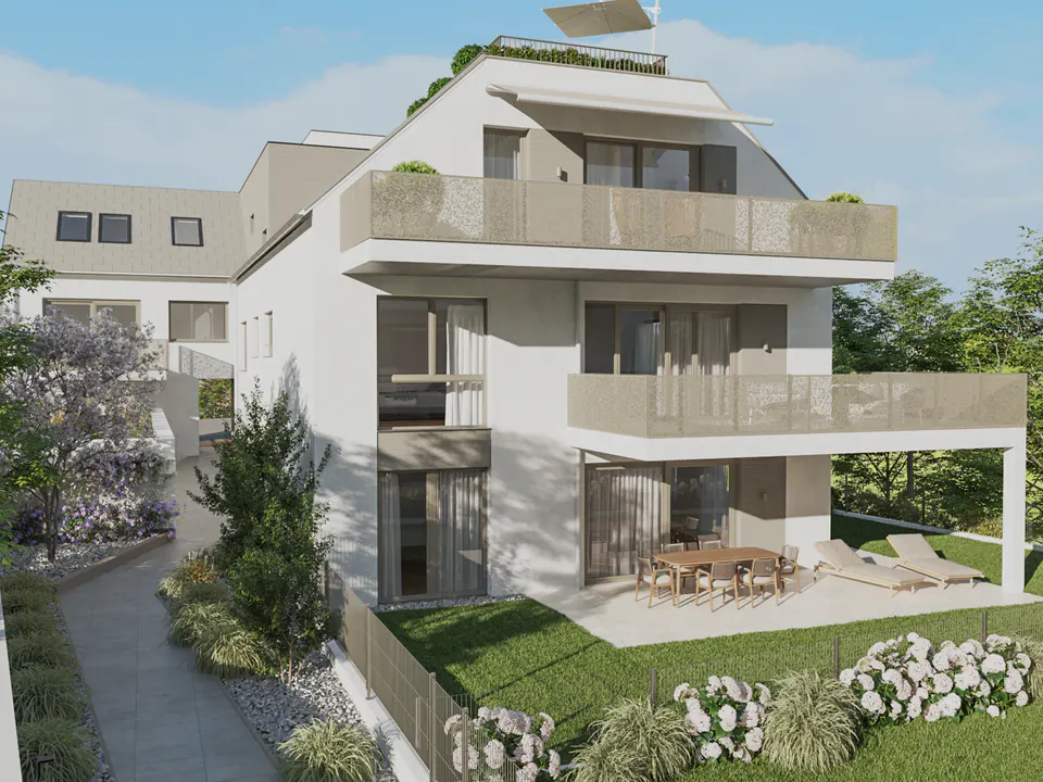Three-story white building with balconies, a patio with a table and chairs, and a green lawn with flowers.