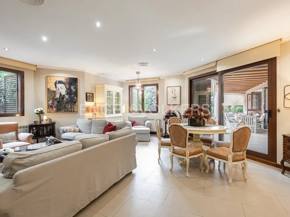 Bright living room with a large beige sofa, round table with chairs, and sliding glass doors to an outdoor patio.