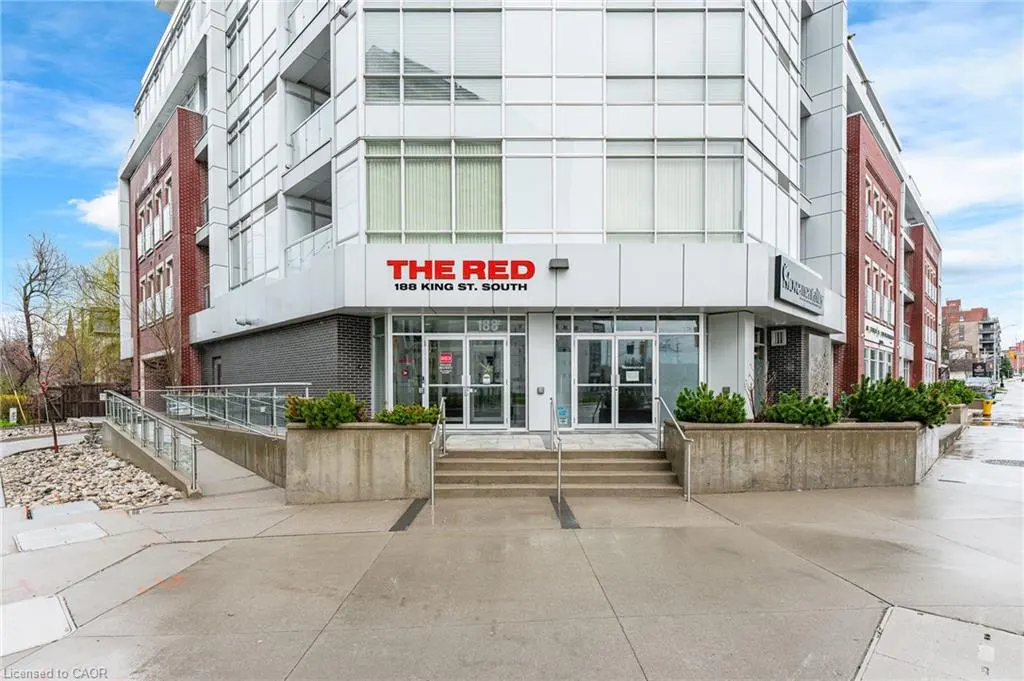Exterior shot of "The Red" building at 188 King St. South, featuring a modern white facade with red brick accents. Glass doors lead into the building.