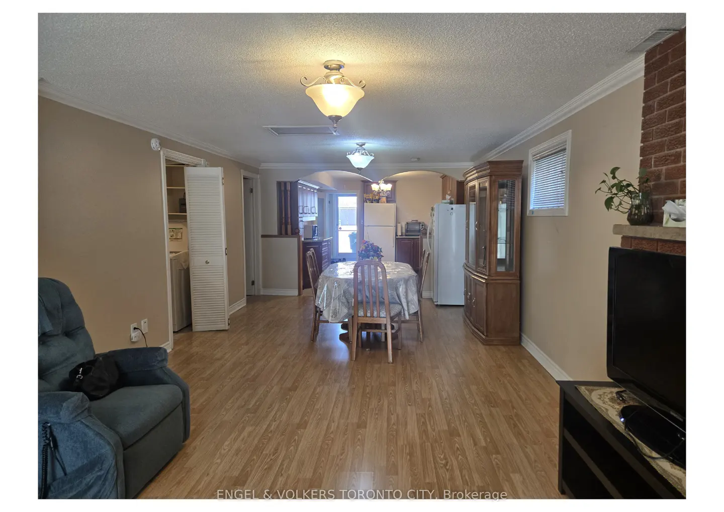 A bright, open-concept living and dining area with wood floors, a dining table, and a blue recliner.
