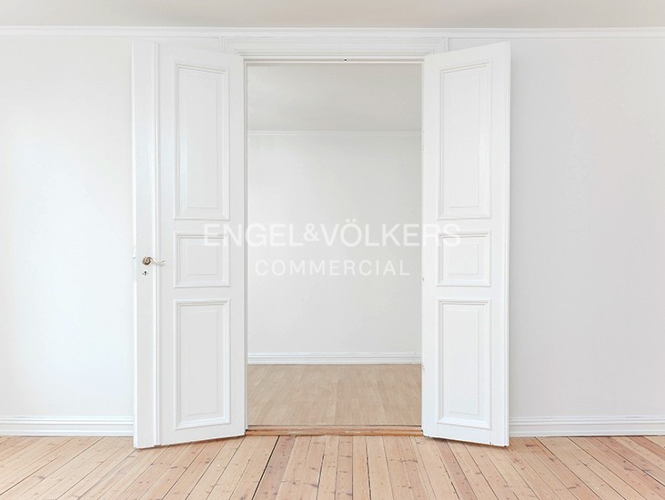 Open white double doors leading to an empty room with light wood flooring and white walls. [AI-generated text]