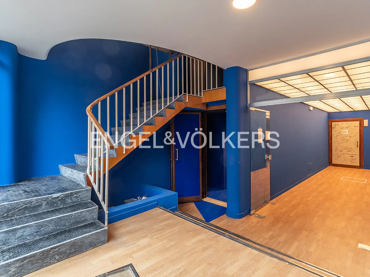 Modern interior with vibrant blue walls, a wooden staircase with metal railings, and light wood flooring.