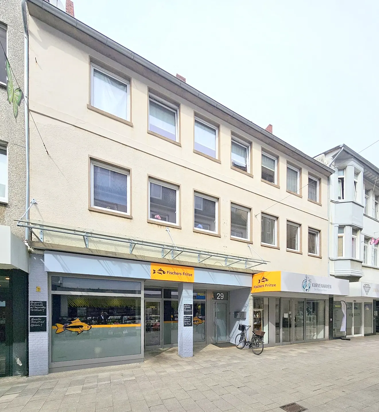 Three-story building with commercial space. "Fischers Fritze" restaurant on the ground floor. Bike parked outside.
