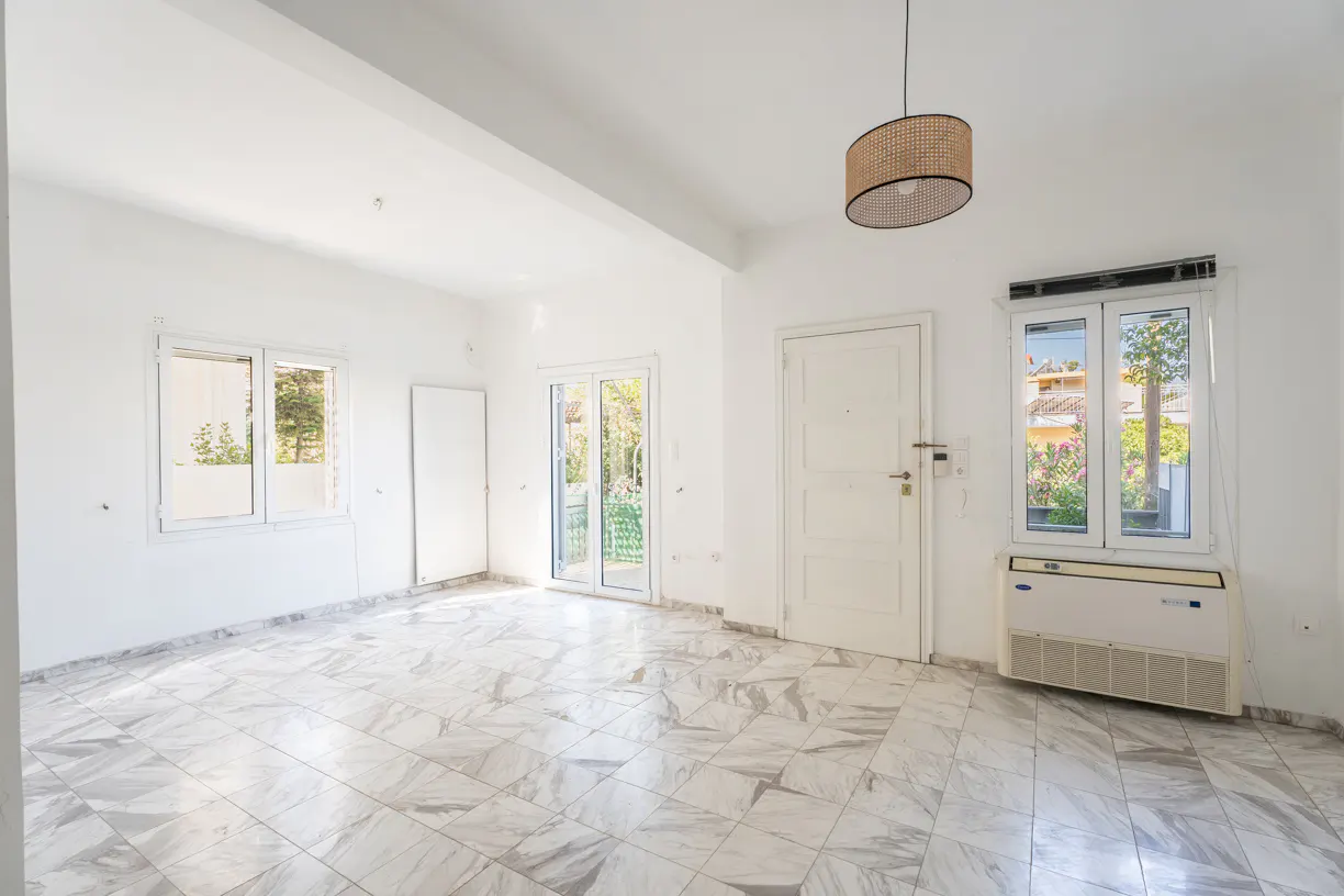 Bright, empty room with white walls, marble-patterned tile floors, a modern pendant light, and windows overlooking greenery.