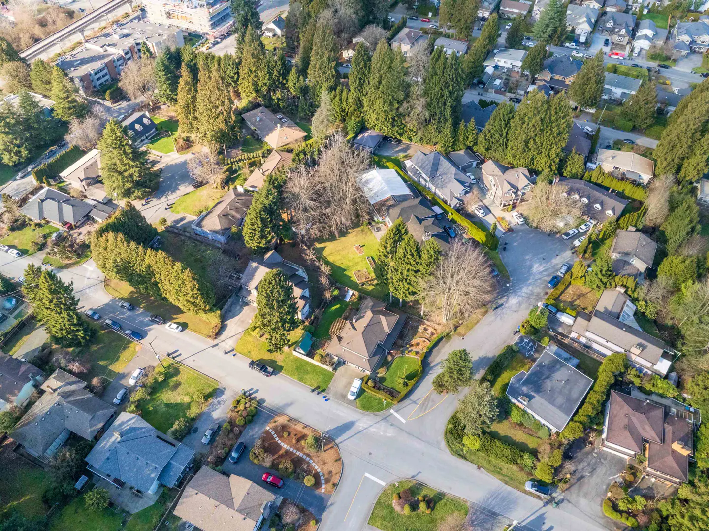 Aerial view of a residential neighborhood with houses, trees, and streets on a sunny day.