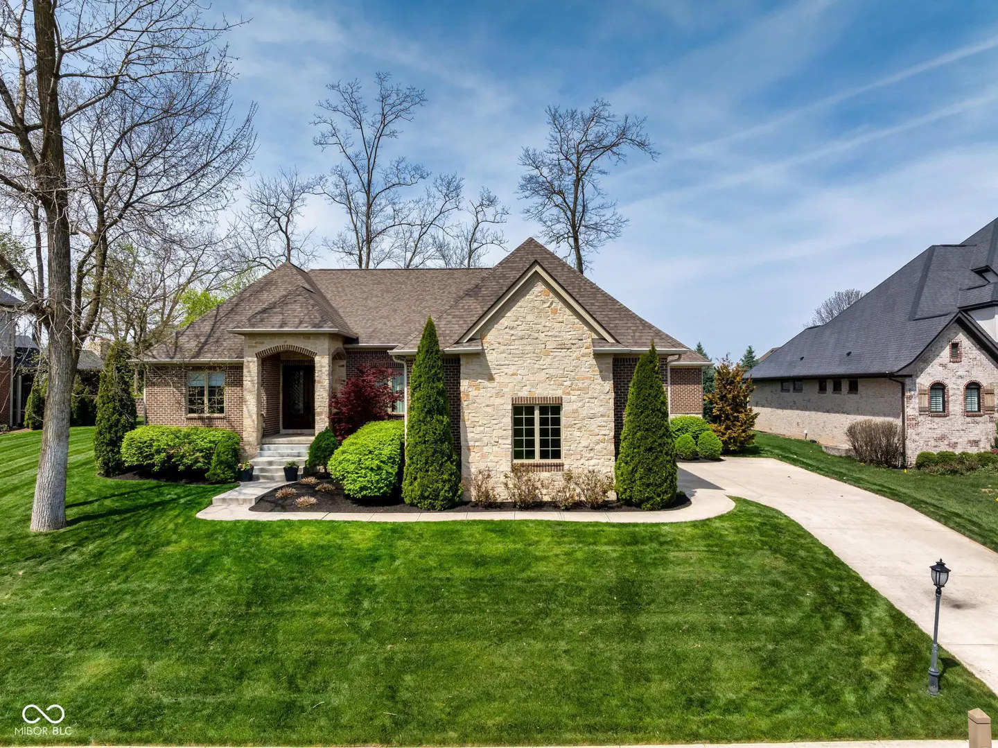 A single-story house with a brick and stone facade, a brown roof, and a well-manicured green lawn.