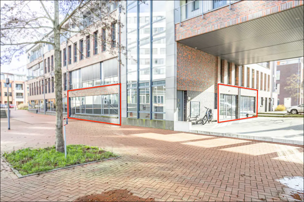 Exterior view of a modern brick building with large windows, a brick walkway, and a tree.