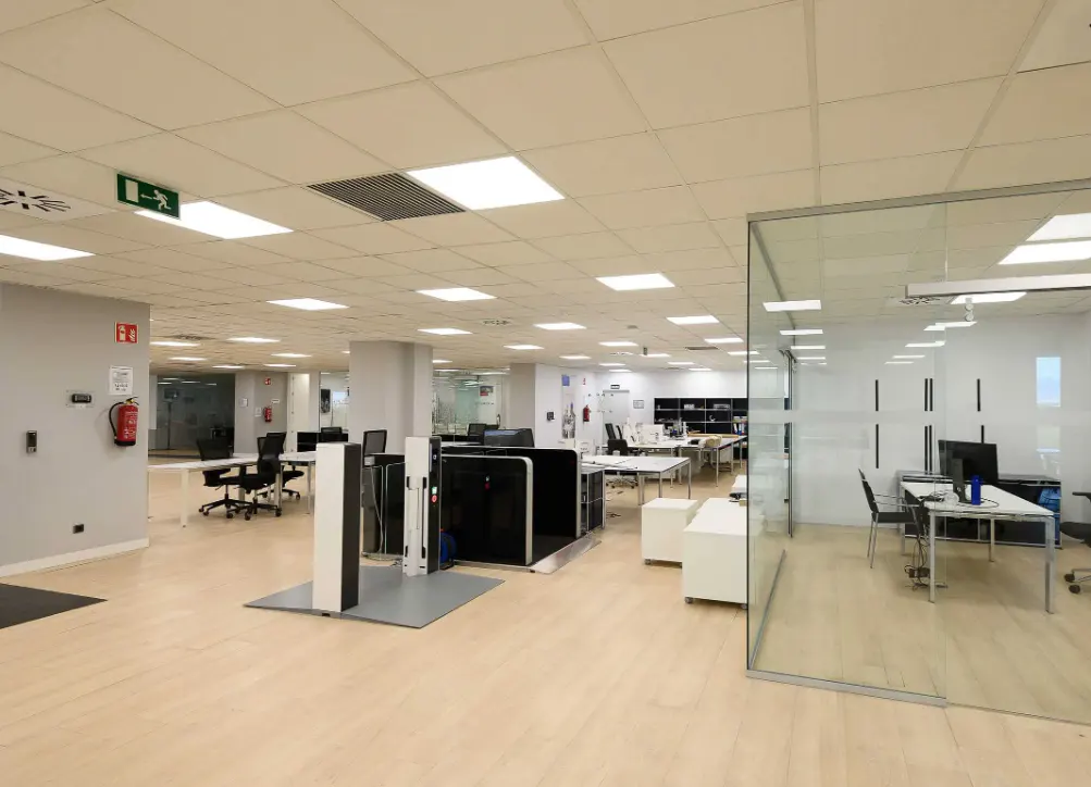 Bright, modern office space with white desks, black chairs, and glass-walled conference room.