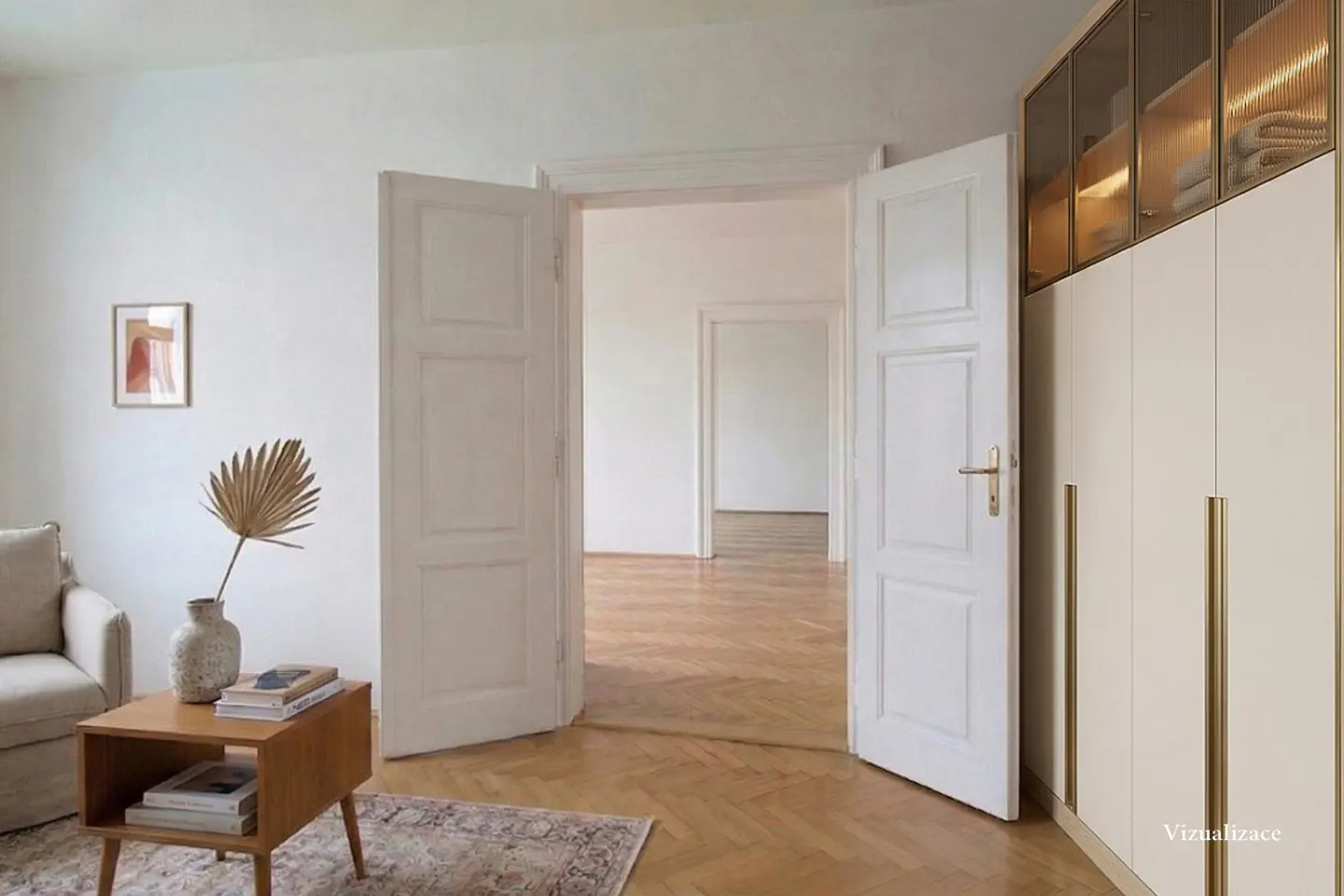 Bright room with open white doors, wood floors, and a beige wardrobe with glass doors. A small table with books and a vase sits near a beige sofa.