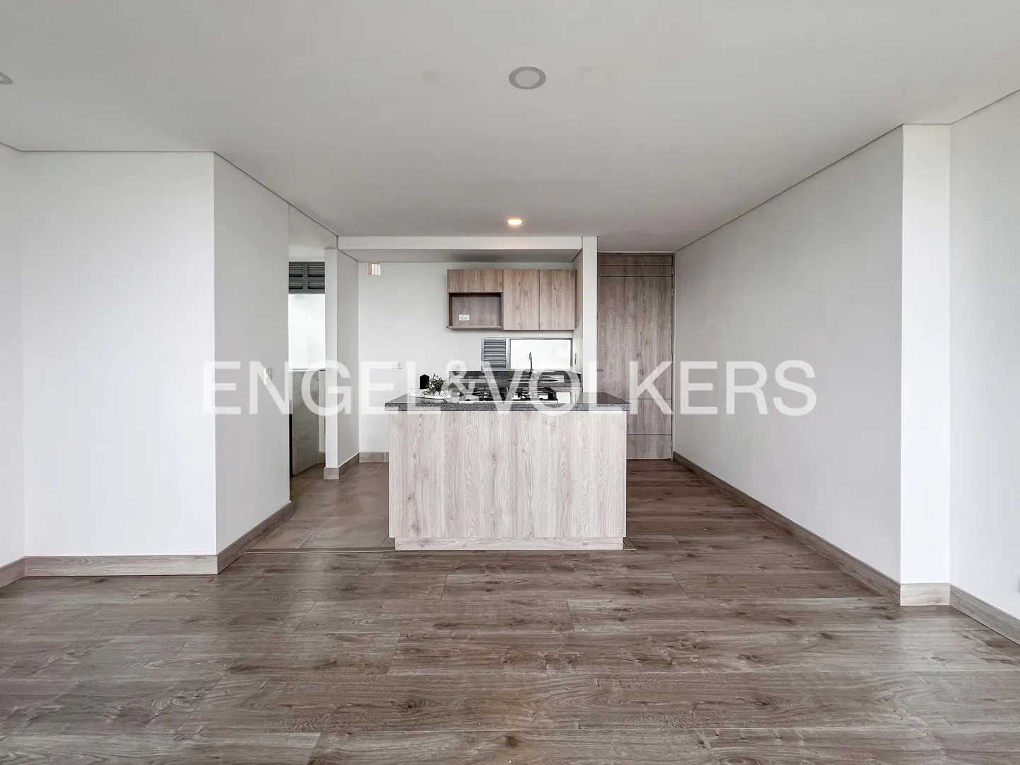 Open-concept kitchen and living area with wood floors, white walls, and a light wood kitchen island.