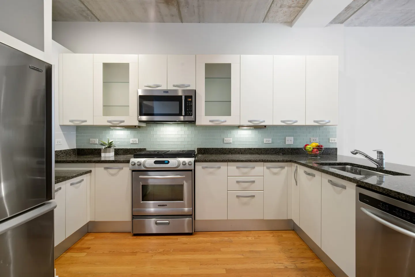 A modern kitchen with white cabinets, stainless steel appliances, and granite countertops.