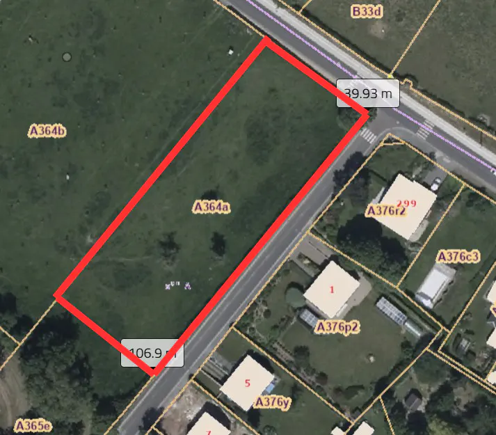Aerial view of a grassy lot outlined in red, adjacent to a road and houses. The lot is labeled A364a.
