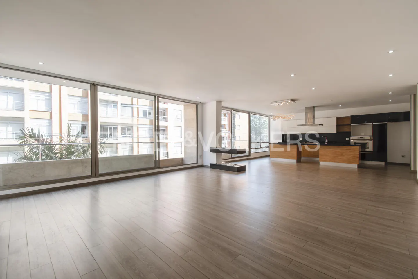Bright, open-concept apartment with wood floors, floor-to-ceiling windows, and a modern kitchen with black and white cabinets.