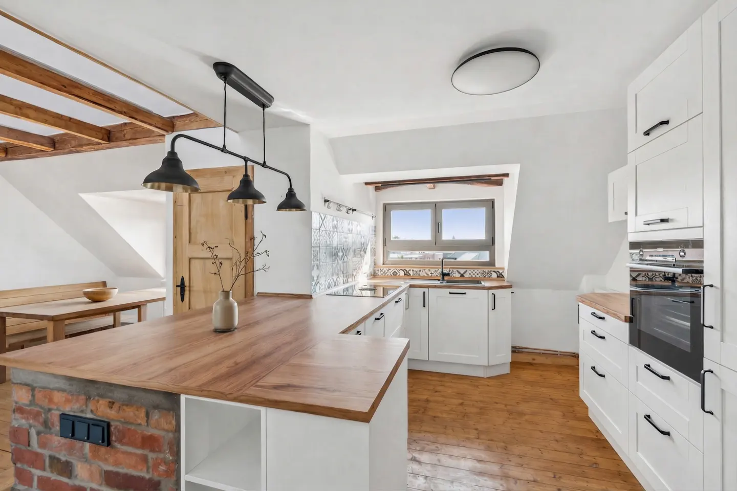 Bright kitchen with white cabinets, wood countertops, and brick island base. Black pendant lights hang above the island.