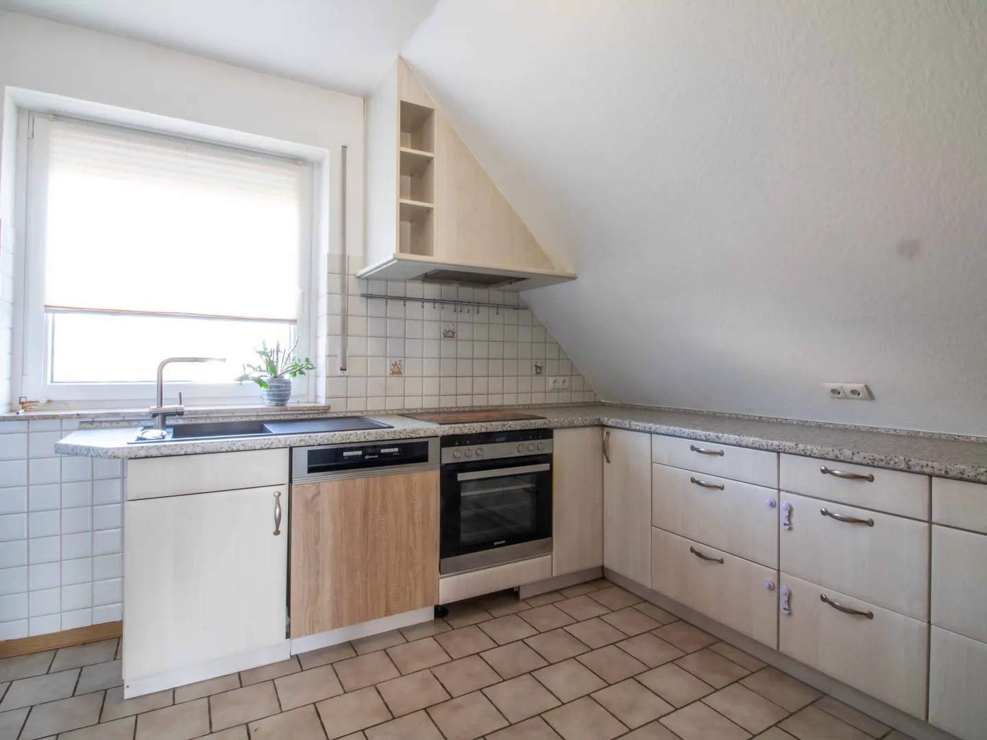 Bright kitchen with white cabinets, granite countertops, and tile floors. A window is above the sink.