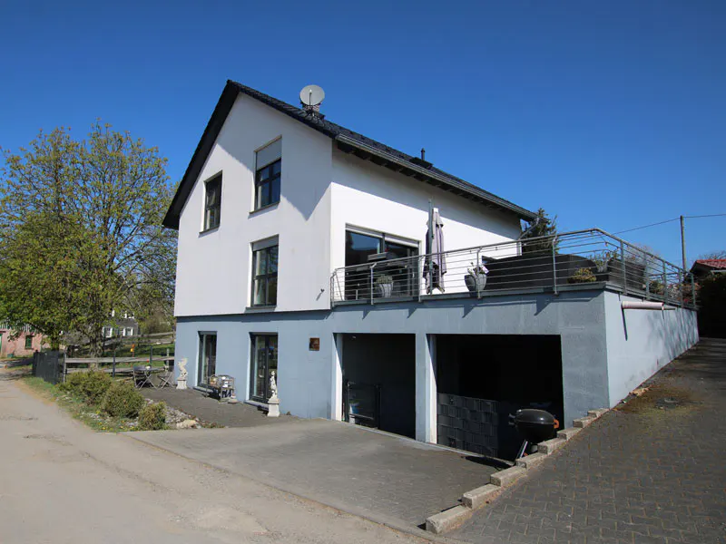 Two-story house with a gray base, white upper level, balcony, and two-car garage.