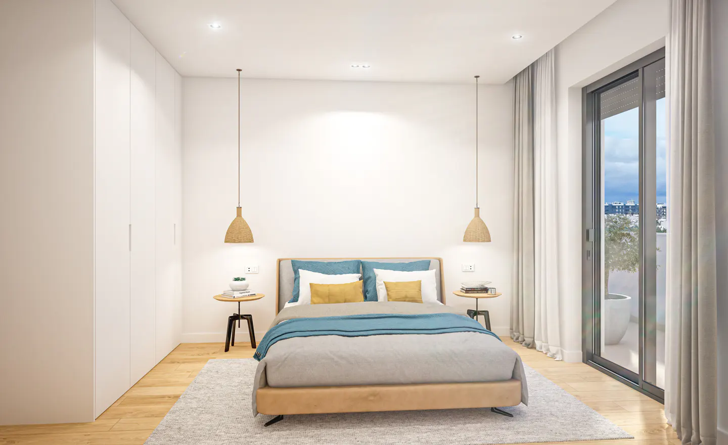 Bright bedroom with a wood floor, white walls, and a large window. A bed with blue and yellow pillows sits on a gray rug. Two pendant lights hang above small side tables.