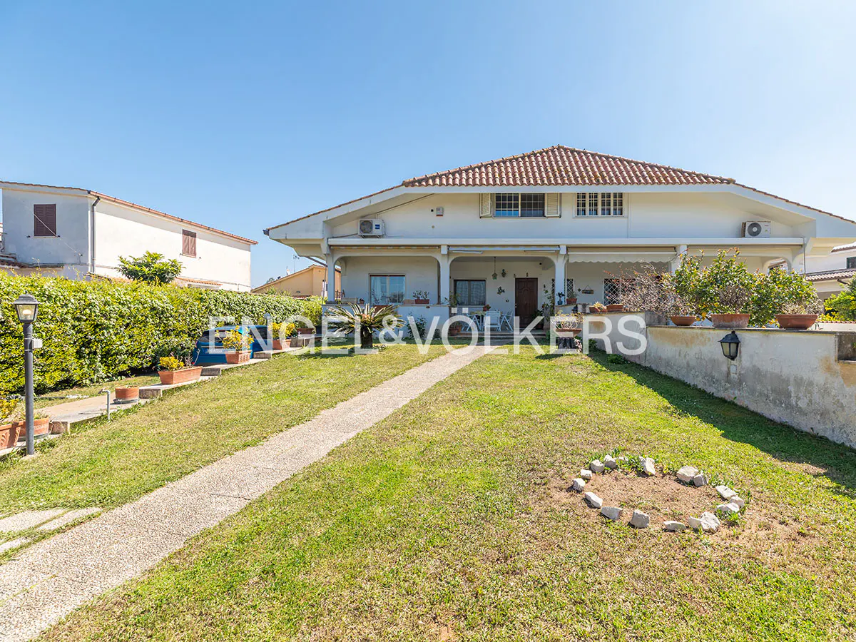 Exterior of a two-story white house with a red tile roof, a stone walkway, and a green lawn.
