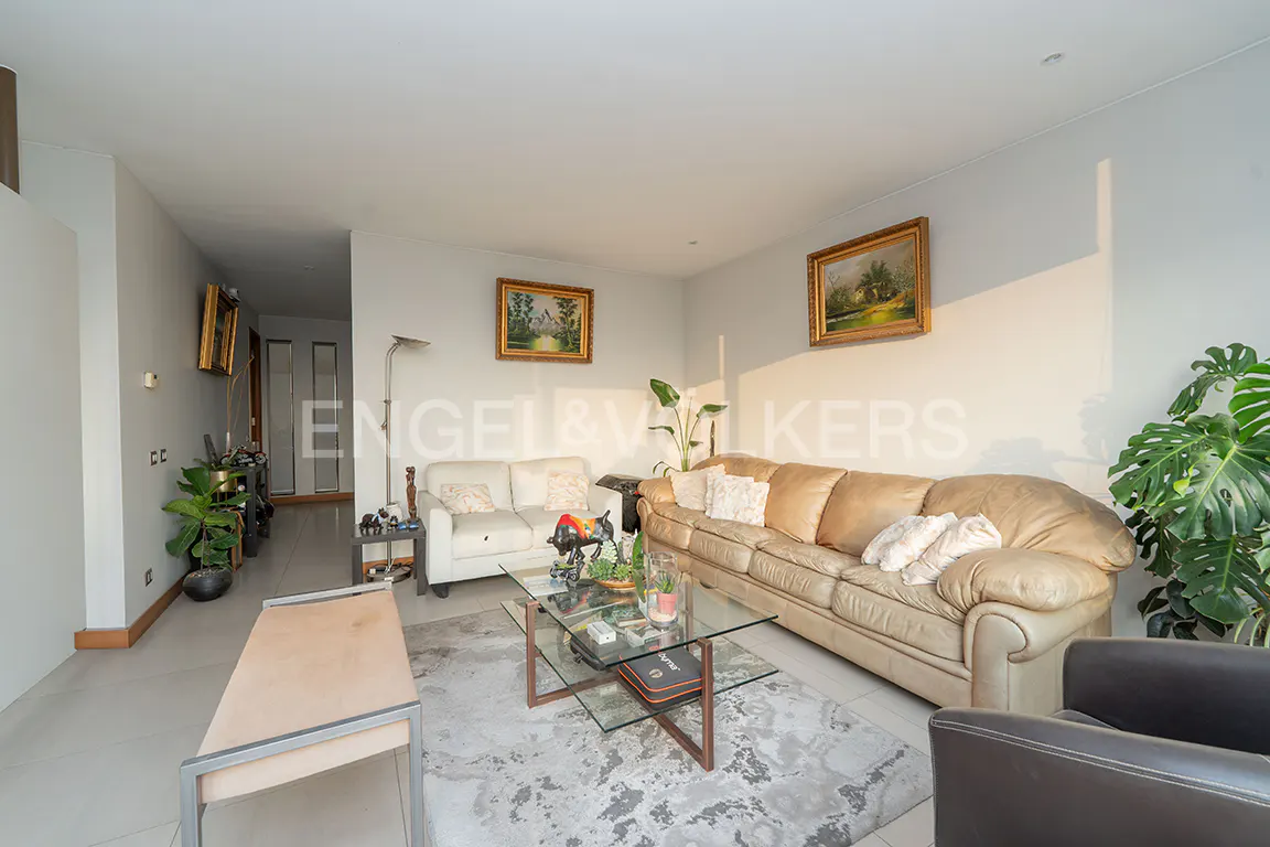 Living room with beige and white sofas, glass coffee table on a gray rug, and framed art on the walls.
