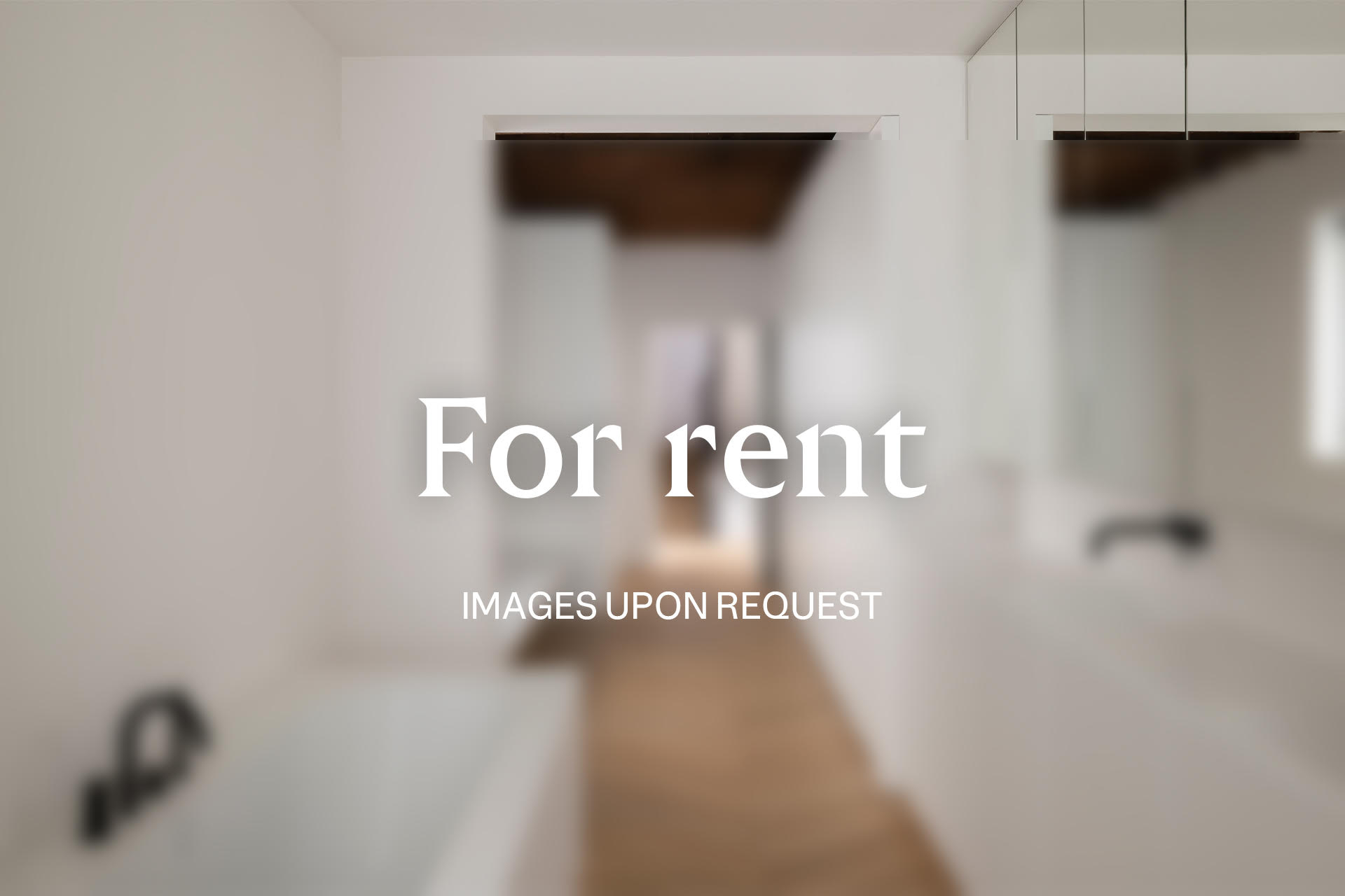 Blurred view of a white bathroom with a glimpse into a hallway. Text overlay reads "For rent, images upon request."
