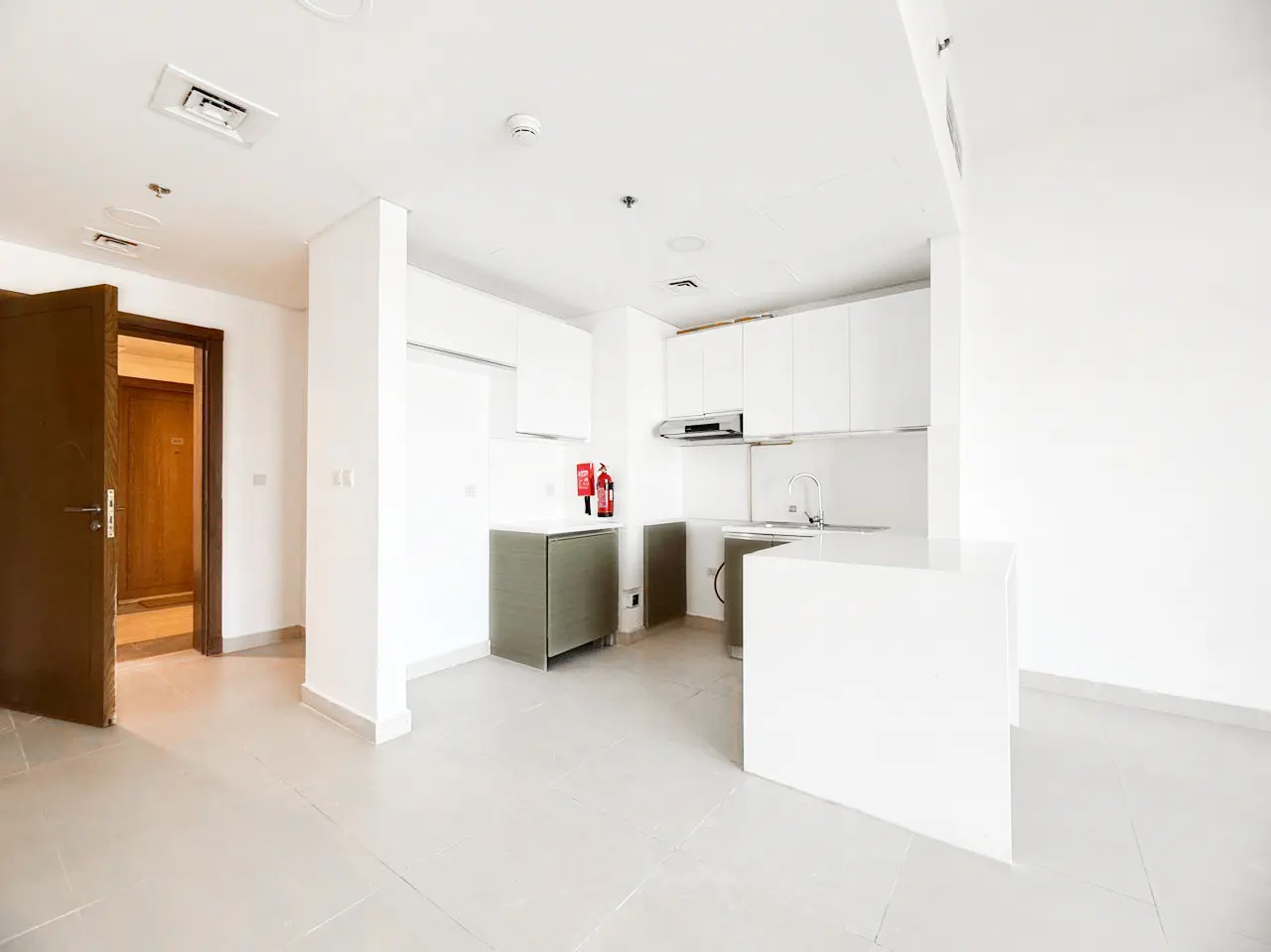 Modern kitchen with white cabinets, a white island, grey lower cabinets, and a doorway leading to a wooden door.