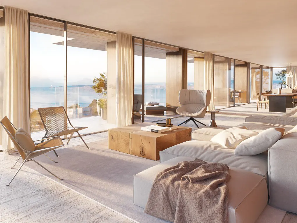 Bright, modern living room with floor-to-ceiling windows overlooking the ocean. Features a white sofa, wooden coffee table, and stylish chairs.