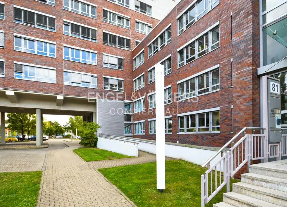 Exterior view of a red brick commercial building with many windows and the Engel & Volkers logo.