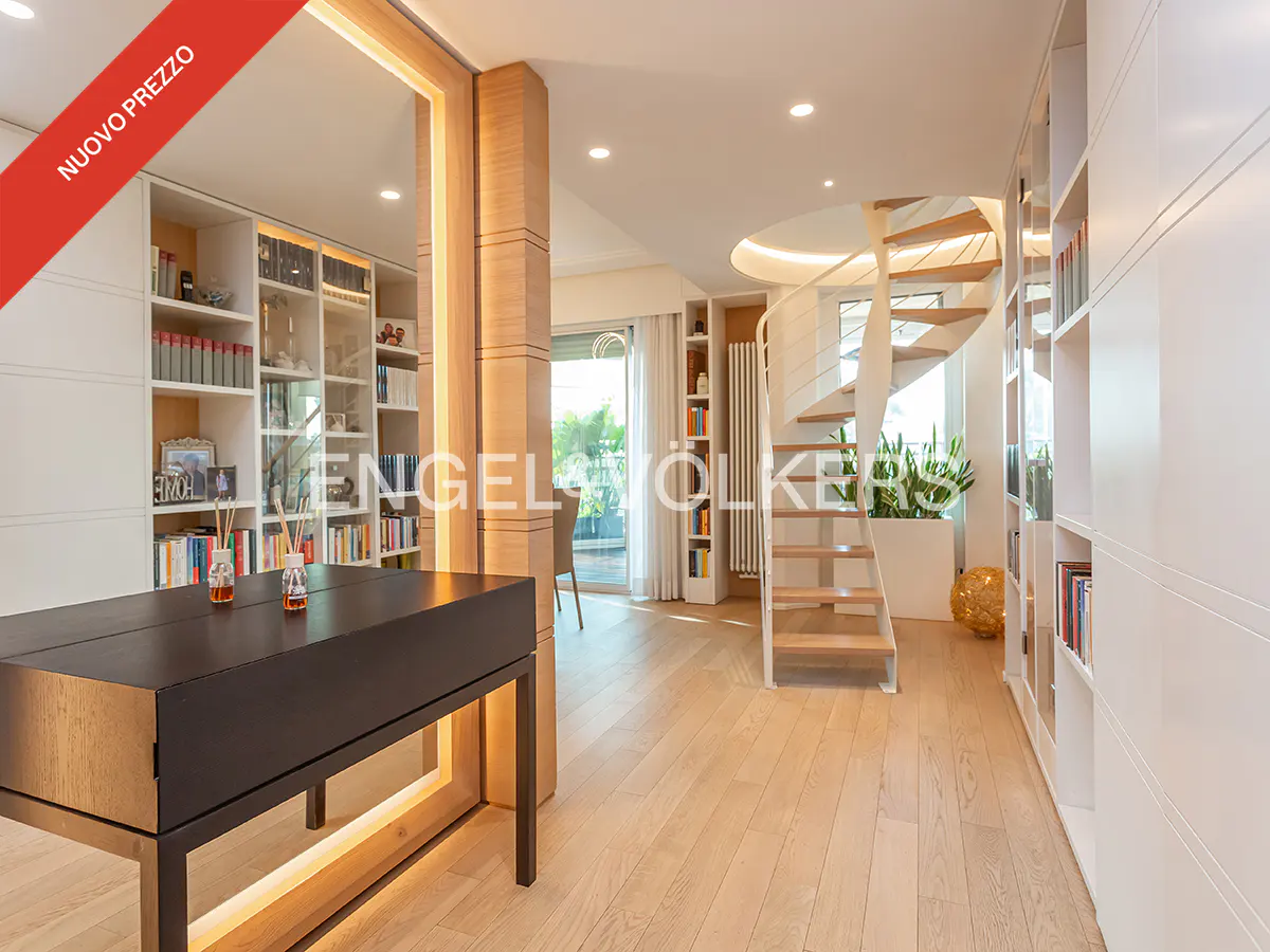 Bright, modern interior with light wood floors, white bookshelves, and a spiral staircase. A dark desk sits in front of a mirrored wall.