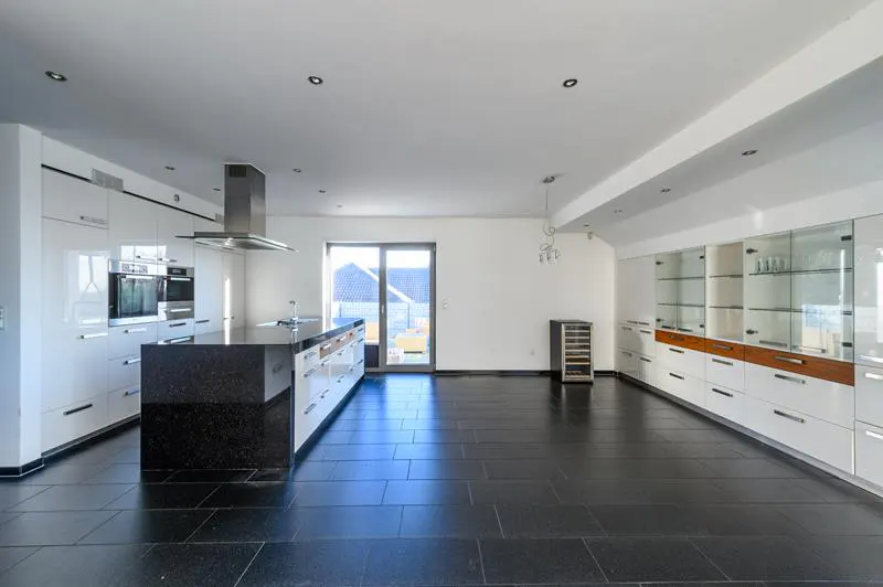 Bright, modern kitchen with black tile floor, white cabinets, and a black granite island. Stainless steel appliances and a wine cooler are visible.