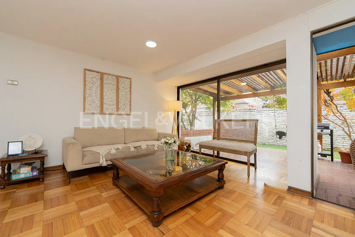 Living room with parquet floors, beige sofa, wooden coffee table, and sliding glass doors to a patio.