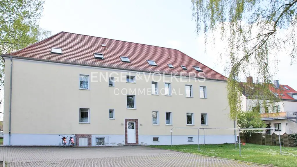 Exterior view of a three-story beige building with a red tile roof and multiple windows. The Engel & Völkers logo is visible on the building's facade.