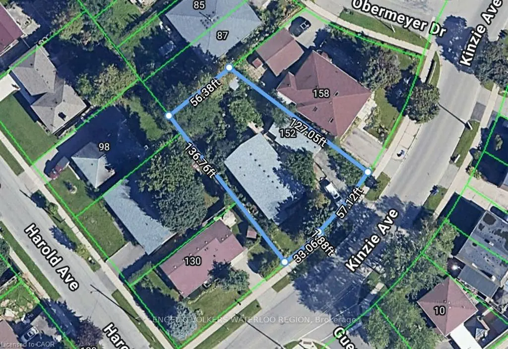 Aerial view of a property outlined in blue, showing dimensions, surrounded by houses and streets. Green trees and lawns fill the landscape.