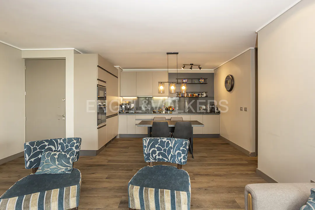 Open-concept living space with wood floors, a kitchen with a dining table, and blue patterned chairs.