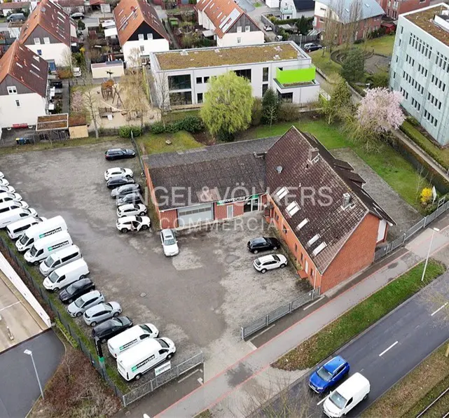 Aerial view of an Engel & Völkers commercial property with a large parking lot filled with cars and vans.