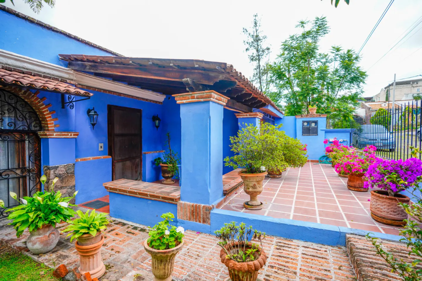 Exterior of a blue house with a brick patio and potted plants.