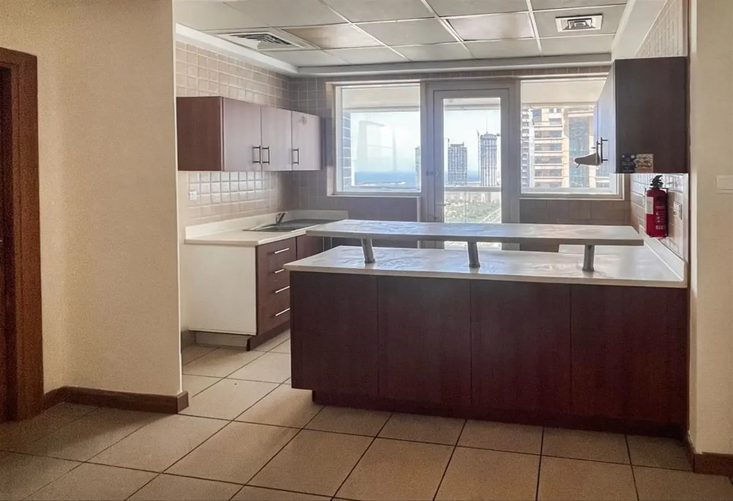 Kitchen with brown cabinets, white countertops, a breakfast bar, and a window view of city skyscrapers.