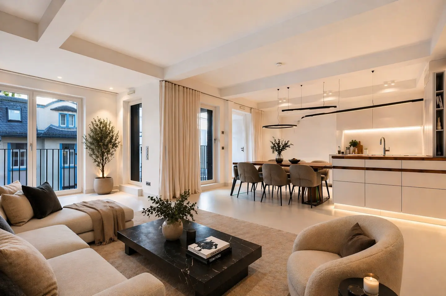 Bright, open-concept living space with a beige sectional, marble coffee table, dining table, and white kitchen. Neutral tones throughout.
